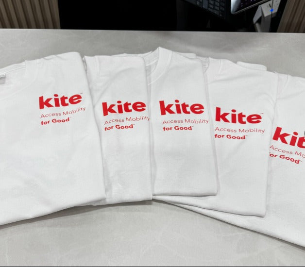 Folded white Kite Mobility team t-shirts lined up after production