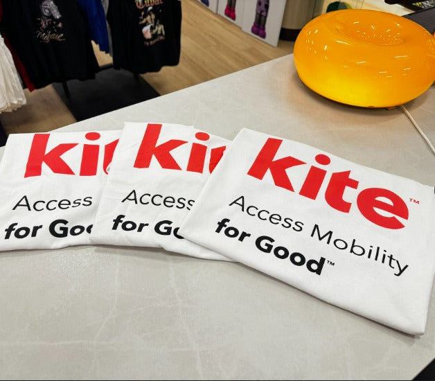 Three folded Kite Mobility branded t-shirts on a table at Urban Customz