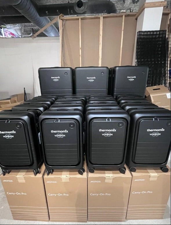 Thermomix by Vorwerk branded Monos Carry-On Pro suitcases stacked on their shipping boxes