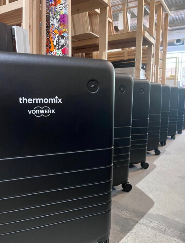 A Monos hard-shell suitcase branded with the Thermomix by Vorwerk logo, part of a bulk order produced by Urban Customz